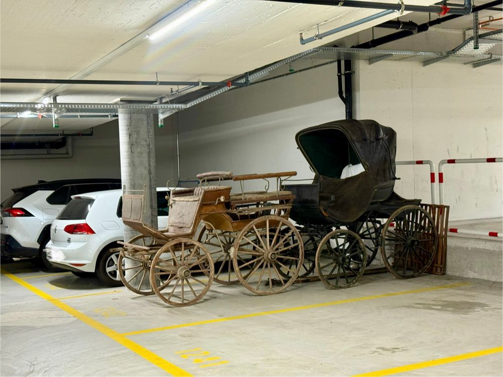 Bild von zwei geparkten, antiken Kutschen in einem grossen Parkhaus