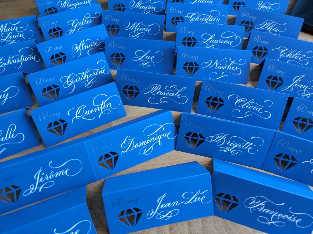 Marque place bleu avec un diamant perforé et des prénoms en blanc avec des ornements