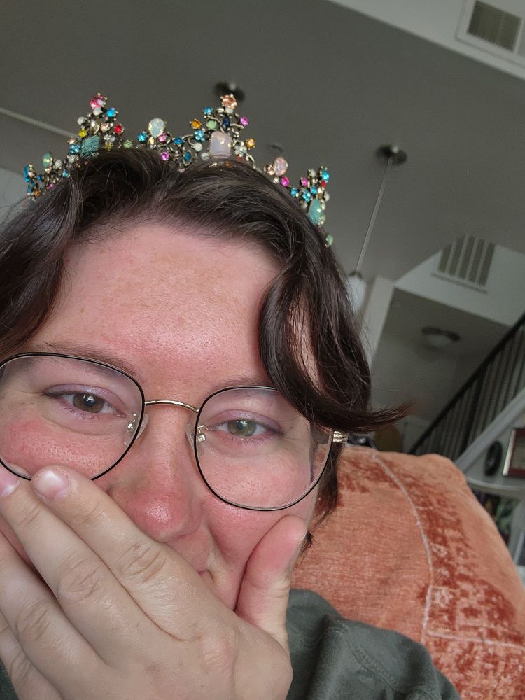 Person holding back tears, hand pressed to mouth, wearing a crown to instill enough courage to press the submit button on the query manager