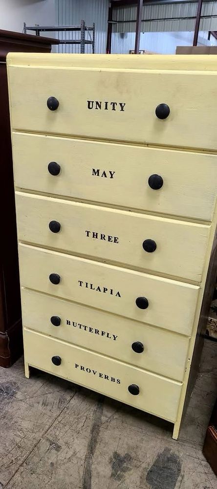 A dresser with six shelves, each with a word on them. The words are “Unity”, “May”, “Three”, “Tilapia”, “Butterfly”, and “Proverbs”