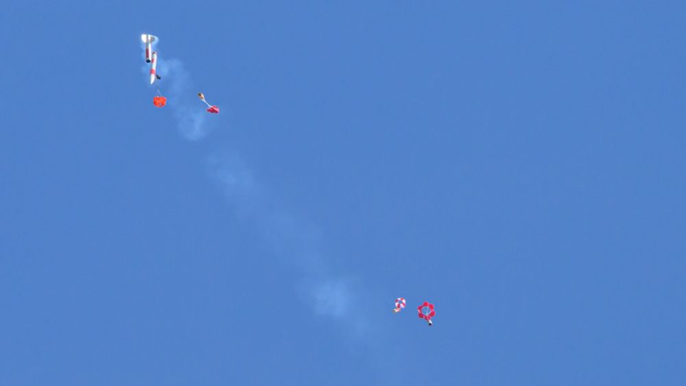 CanSats schweben an Fallschirmen zu Boden

Links im Bild sind die Rakete und ein Dosensatellit zu sehen, deren Fallschirme sich gerade öffnen. Rechts im Bild sind zwei Dosensatelliten mit bereits geöffnetem Fallschirm, an dem sie zu Boden schweben. Am Boden angekommen werten die Schulteams die Missionen ihrer Satelliten aus.