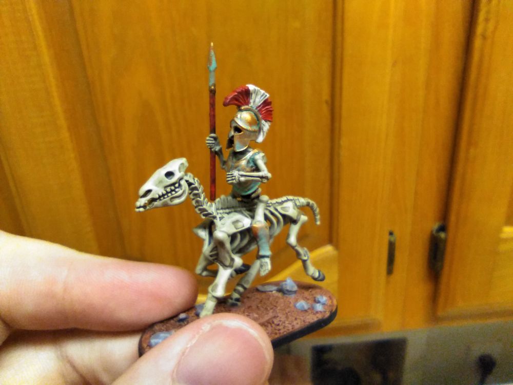 Miniature: Cavalry sergeant, spear held straight up. Red spear shaft, verdigris tip. Corroded bronze breastplate and helmet.