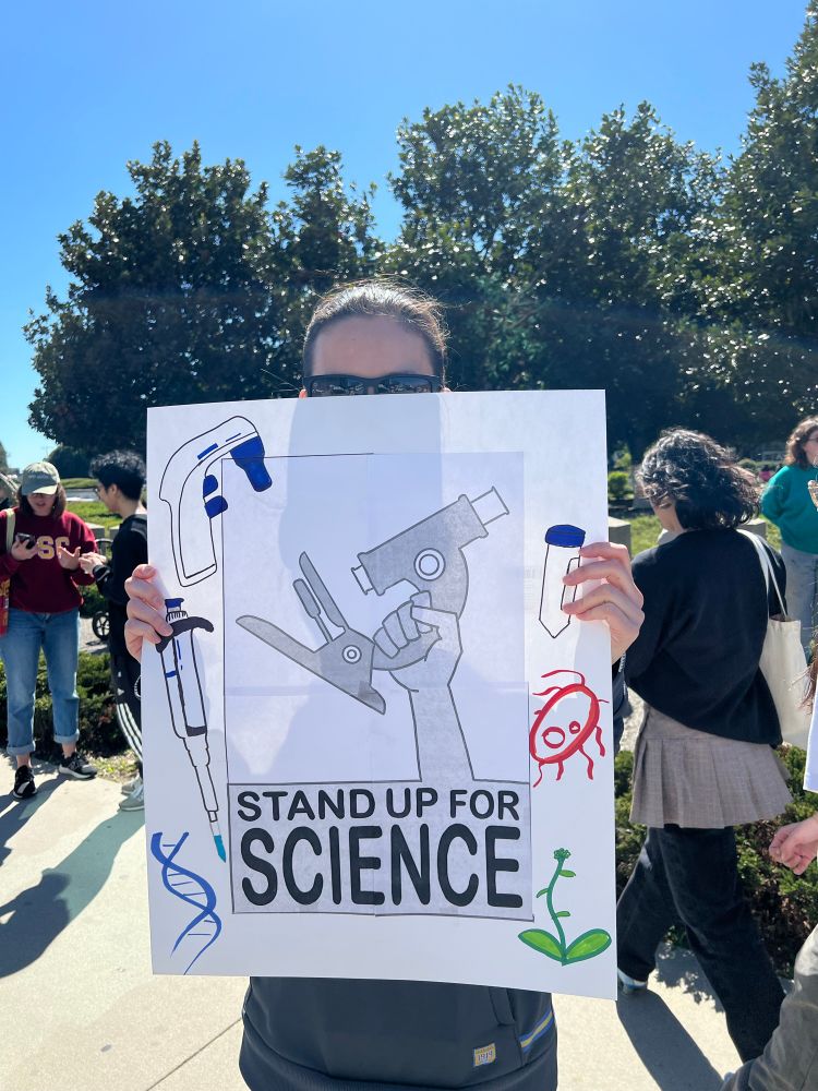 Stand Up For Science sign in Los Angeles with microscopes, plants, pipettes, 50ml tube and DNA drawn on it
