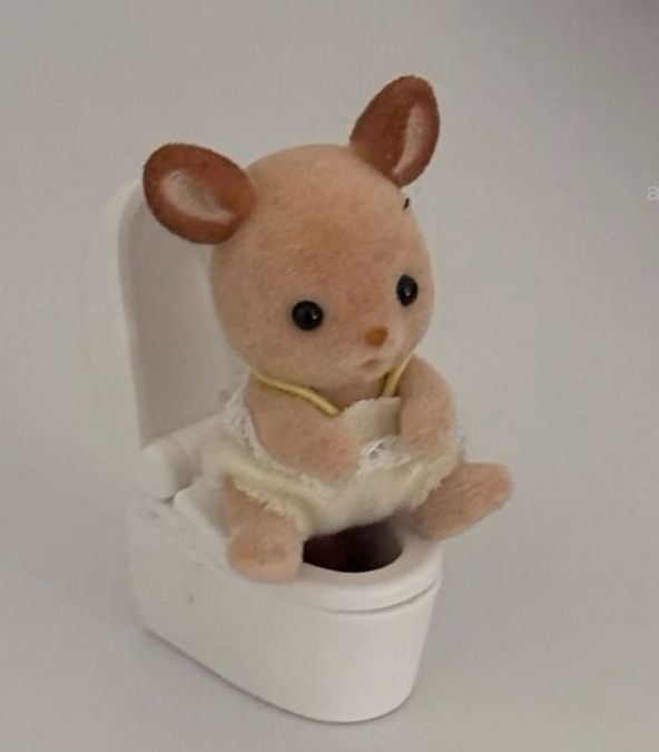 foto de um brinquedo Sylvanian Family bebê sentado em um vaso sanitário