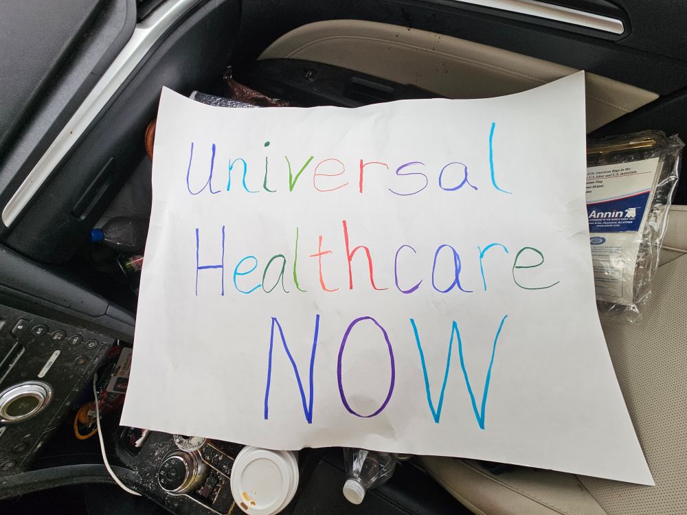 Sign in rainbow colors that says, "Universal Healthcare NOW"