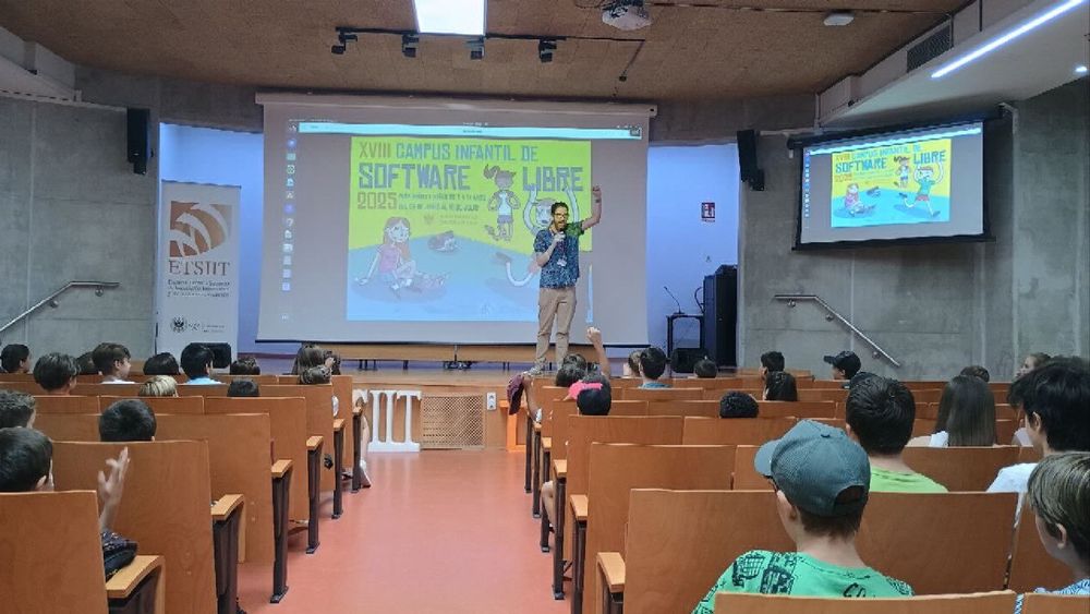 El director de la osl en el salón de actos delante del cartel del campus