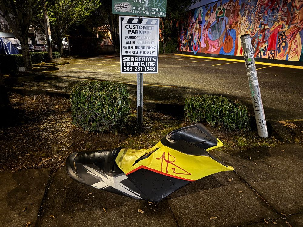 A massive prop shoe laying on the sidewalk. It’s several feet in length and probably about a foot wide and a few feet tall. It looks sort of like sports cleat style shoes, which makes me think it’s from some school’s mascot. The lower part is mostly black, with a silver x on the side. The upper half is bright yellow. Someone else, presumably, tagged some graffiti with a red pen on the yellow. Very curious. Found next to the Musicians Union Local 99 in the Kerns neighborhood of Portland, OR. The Musicians Union Local 99 “is an organization of over 500 musicians in Oregon and SW Washington. We are affiliated with the American Federation of Musicians, which comprises over 60,000 musicians in the United States and Canada.” Per their website: https://afm99.org/about-the-local-afm/ 