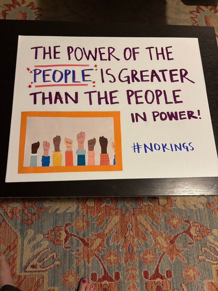 Sign that says “the power of the people is greater than the people in power” with a picture of raised fists in various skin tones attached in one corner 