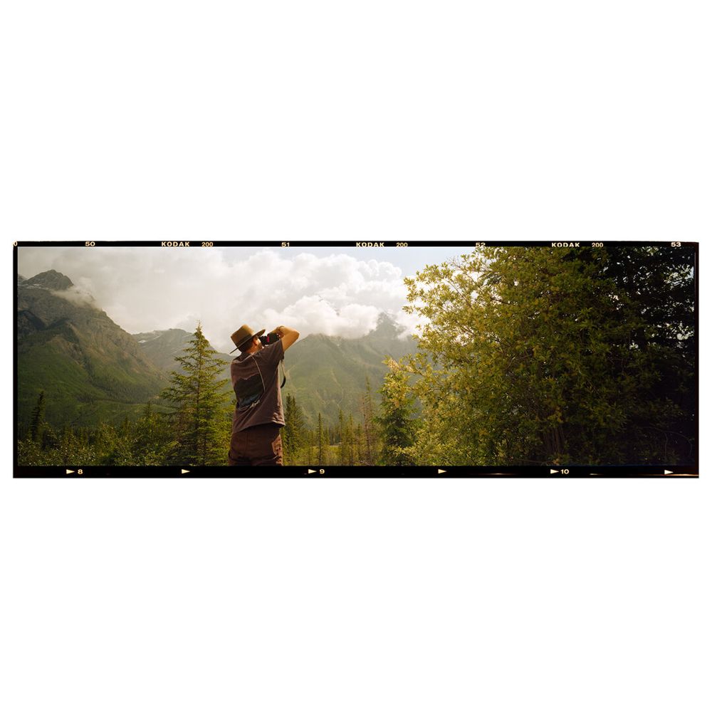 A man standing in front of a landscape. Panoramic image on film.