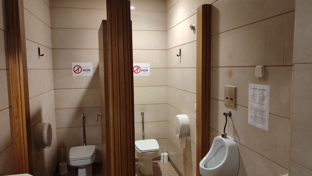 Os cartazes de “Pipí de pé non” estám colocados à altura da vista quando vás mijar de pé no retrete. Os outros estám entre os urinários de parede, e detrás das portas, estrategicamente colocados para que se leiam ao estar sentade no retrete.