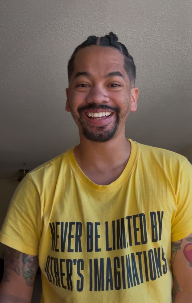 Mychal, with braids and a yellow shirt, smiles