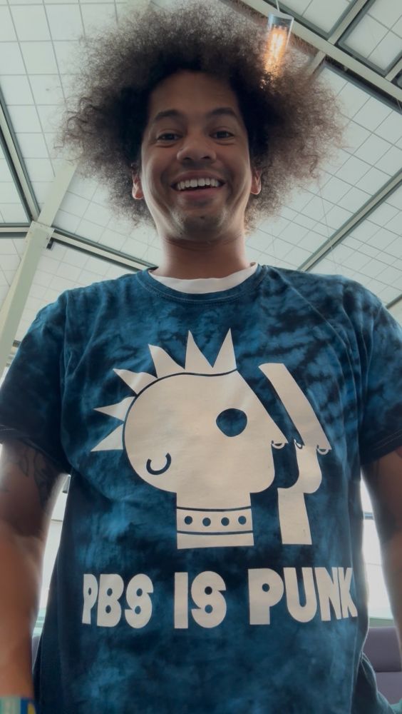 Mychal smiles while wearing a PBS IS PUNK shirt 