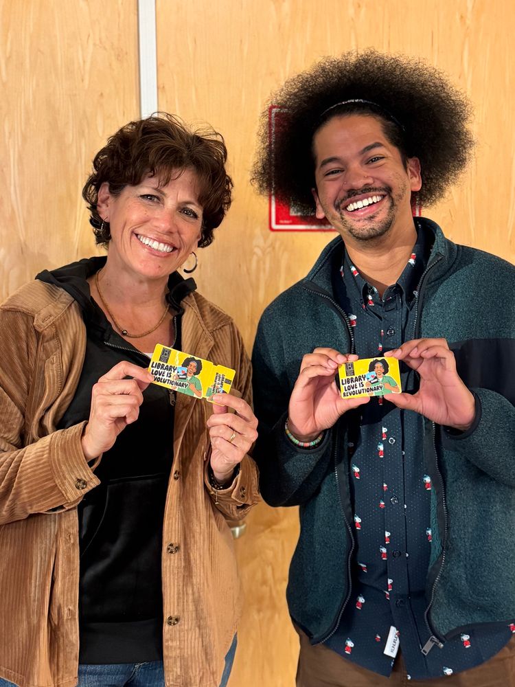 Mychal’s mom and Mychal smile together holding Berkeley Public Library cards 