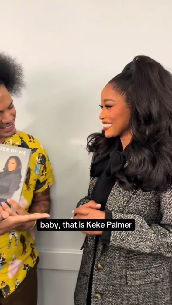 Mychal holds Lauren “Keke” Palmer’s book and points to her, saying, “baby, that is Keke Palmer” as she listens and smiles 