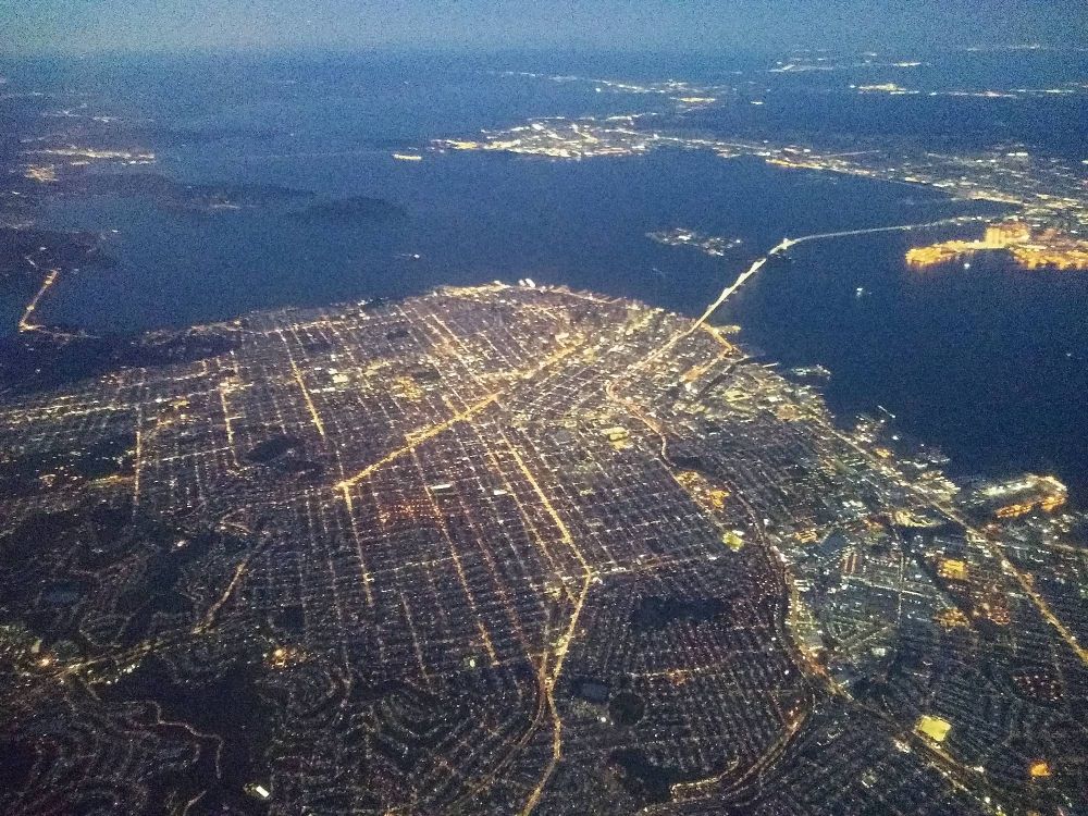 San Francisco on a clear night from an airplane. The lights of the city are surrounded by dark water.