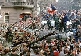 The citizens of Prague surround Russian tanks and armed soldiers, one of whom holds a flag. Taken in the streets of Prague on August 21, 1968.