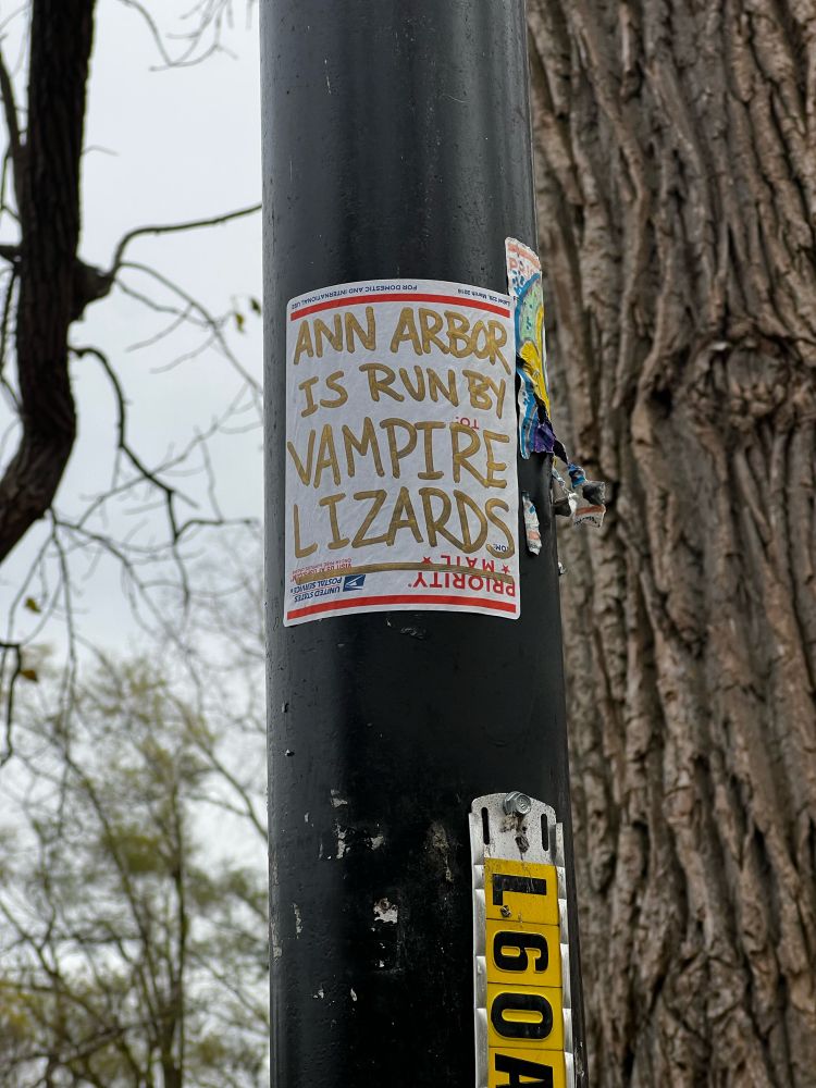 A sticker on a lamp post that says: “Ann Arbor is run by vampire lizards.”