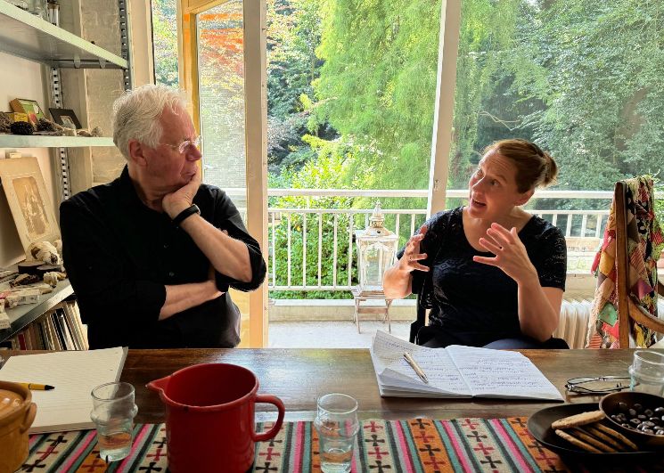Elke in gesprek met voorzitter van de bewonersvereniging, op tafel glazen water , goed drinken in verband met het warme weer, uitzicht op de natuur
