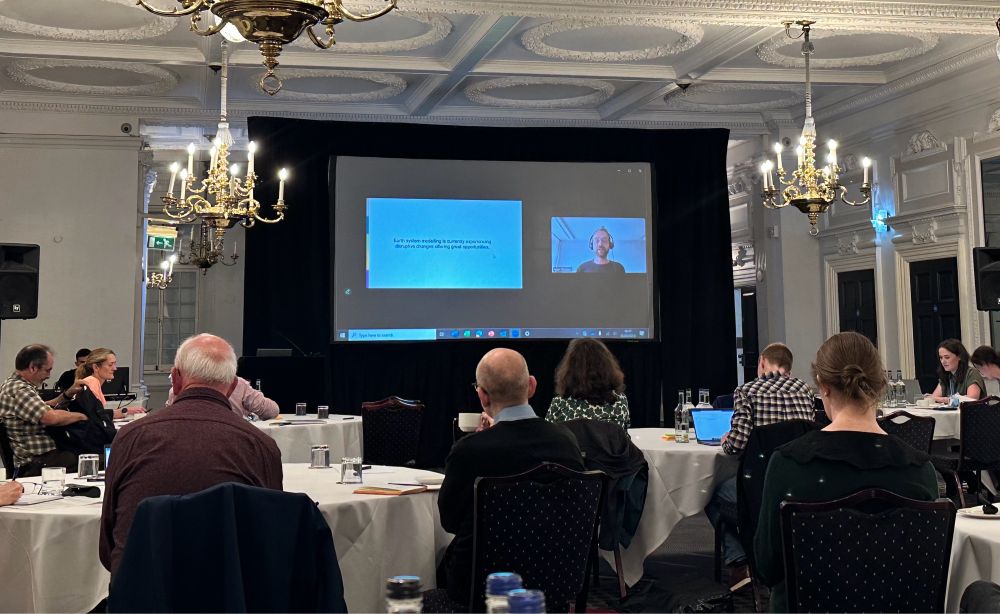 A screen showing a zoom call in a London hotel with Peter Dueben from ECMWF speaking to his first slide.