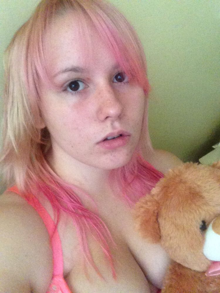 A nineteen year old girl with blonde and pink hair holding a teddy bear.