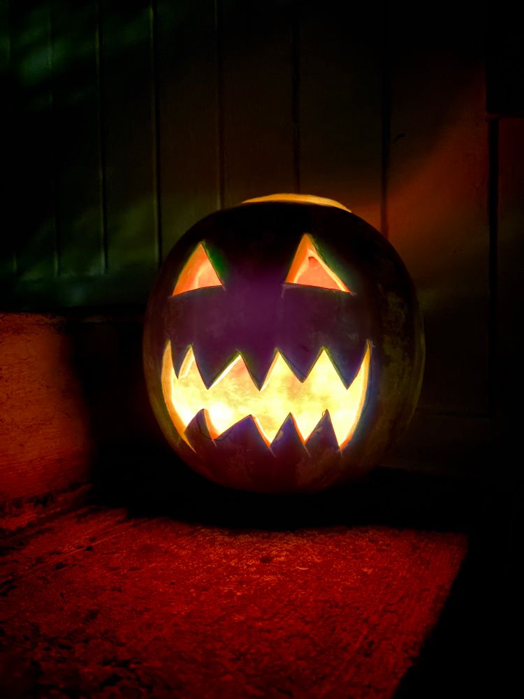 A watermelon jack o lantern lit up in the night 