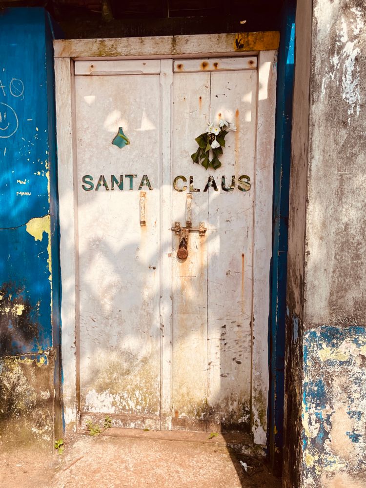 An old and dirty door with a withered mistletoe attached and the words “Santa Claus” stencilled across.