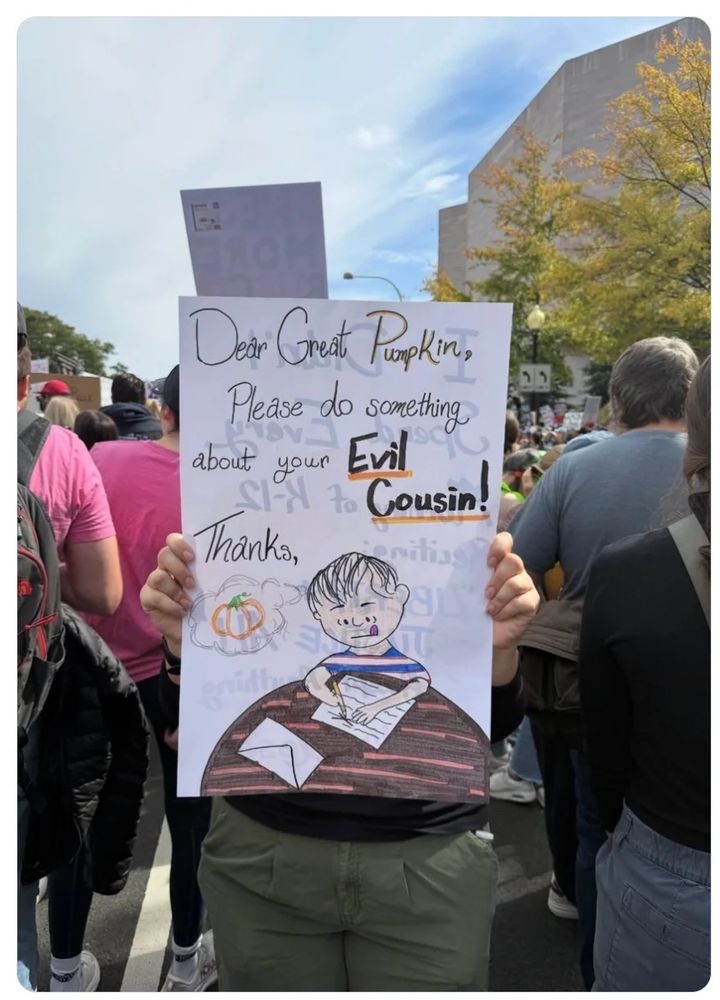 
            The image captures a person standing in a crowd, holding up a handmade sign that features both text and a drawing. The sign is addressed to "Great Pumpkin," which evokes a playful or seasonal tone, commonly associated with Halloween. The main message of the sign is a humorous plea: "Dear Greatt Pumpkin, Please do something about your Evil Cousin! Thanks."

The text is written in a mix of black and purple ink, with the phrase "Evil Cousin!" Trump emphasized in purple and an exclamation mark, suggesting a tone of urgency or frustration. Below the text, there is a colorful cartoon-style drawing of a young person with a disgruntled or unhappy expression, sitting at a table with an envelope and a pencil—elements that suggest the character is writing a letter or complaint. This illustration visually reinforces the message on the sign and adds a personal, expressive touch.

The people surrounding the sign-holder are mostly facing away or are partially obscured, indicating the focus is on the sign itself. The setting appears to be outdoors, perhaps at a rally or protest, given the crowd's density and the presence of other signs in the background.

Symbolically, the reference to "Greatt Pumpkin" and an "Evil Cousin Trump" can be read as a metaphor for addressing a perceived problem caused by a related or associated party—perhaps a political, social, or cultural critique, communicated with humor and artistic expression. The choice of the pumpkin theme may further imply seasonal context or suggest something "rotten" or problematic beneath an outwardly benign appearance, as pumpkins are often symbols of harvest, festivity, and sometimes disguise or transformation.

Overall, the sign combines text and imagery creatively, combining humor, personal expression, and a hint of social commentary in a lively, visually engaging way.
        