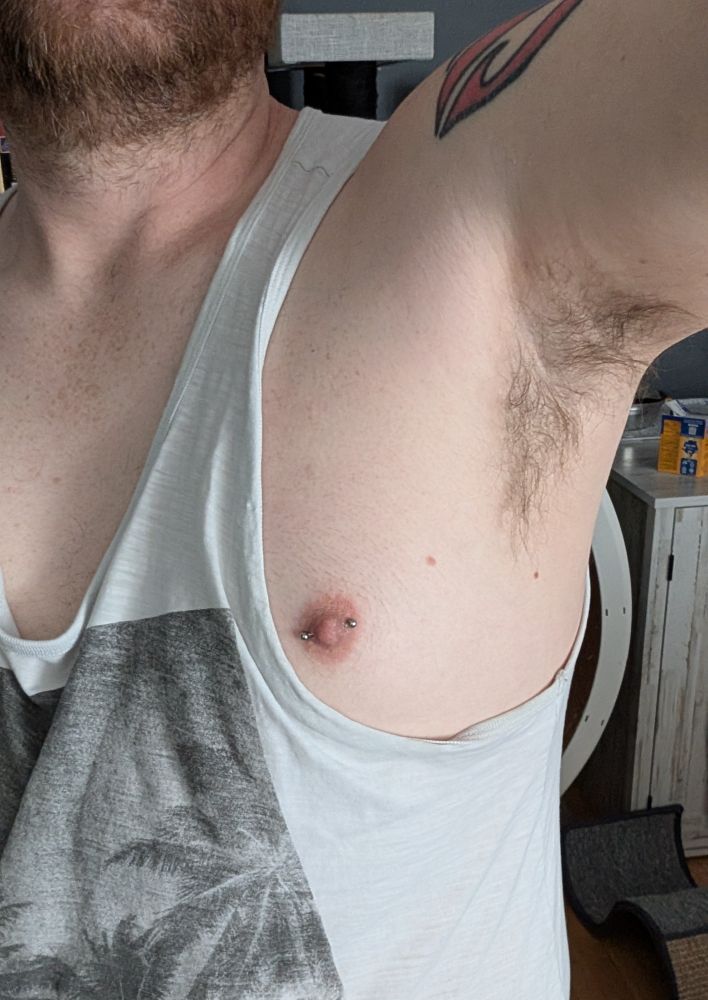 A pic of my pit and pierced nipples; my beard is visible in the shot, and I'm wearing a loose tank top