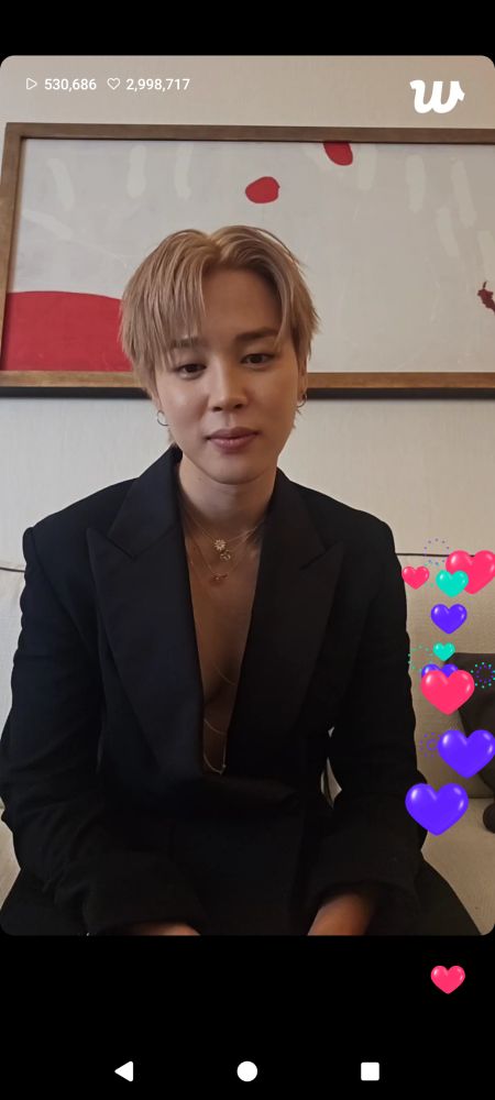 Screenshot of Jimin from a weverse live wearing a black suit with cartoon hearts on the right side of the screen 
