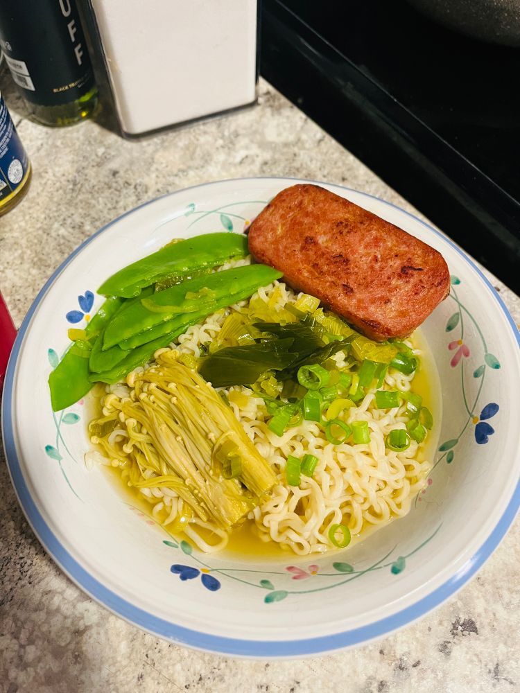 Maruchan ramen noodles in a bowl of onion broth, enoki mushrooms, fried spam, deveined pea pods and scallions. 