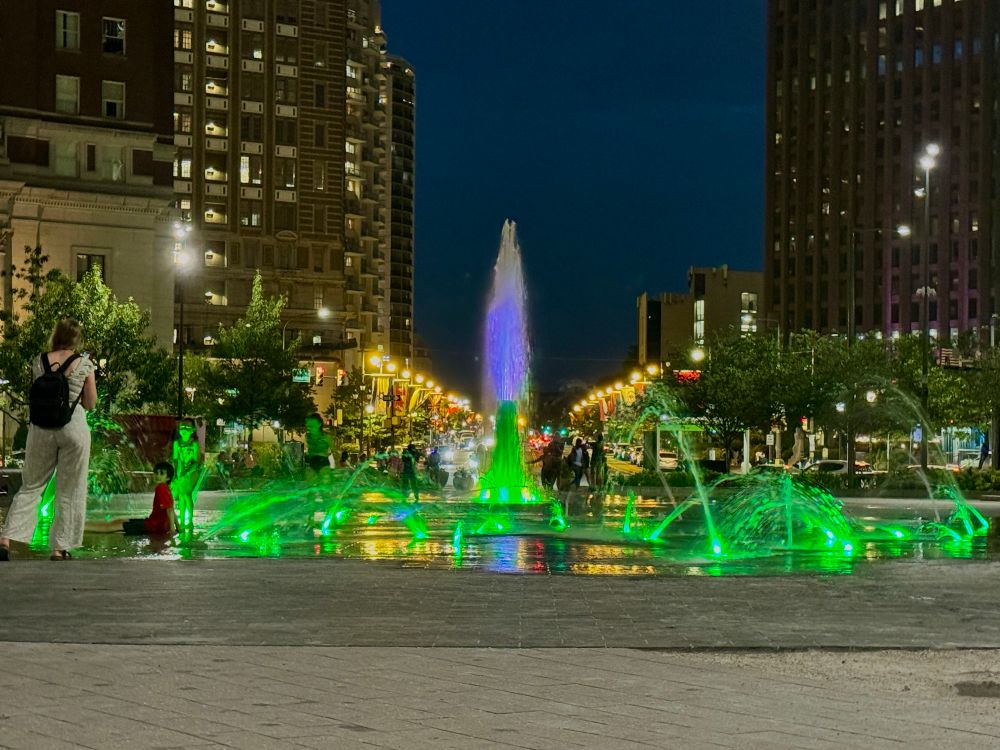 A series of Fountains glows brilliant green during the night in a public plaza in downtown Philadelphia