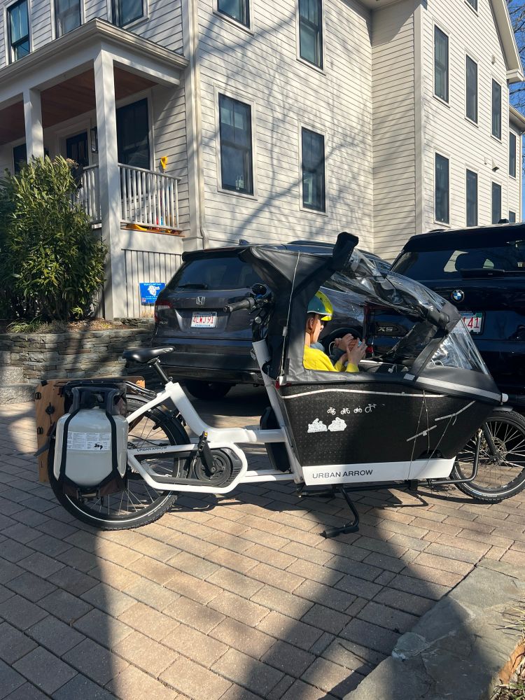 Urban Arrow cargo bike with kids in front and 4 gallon propane tank carried via Bakkie Bag attached to rear rack