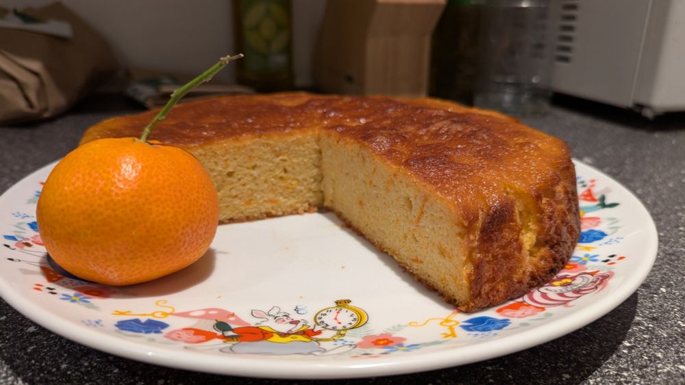 3/4 of a Clementine cake with a Clementine next to it.