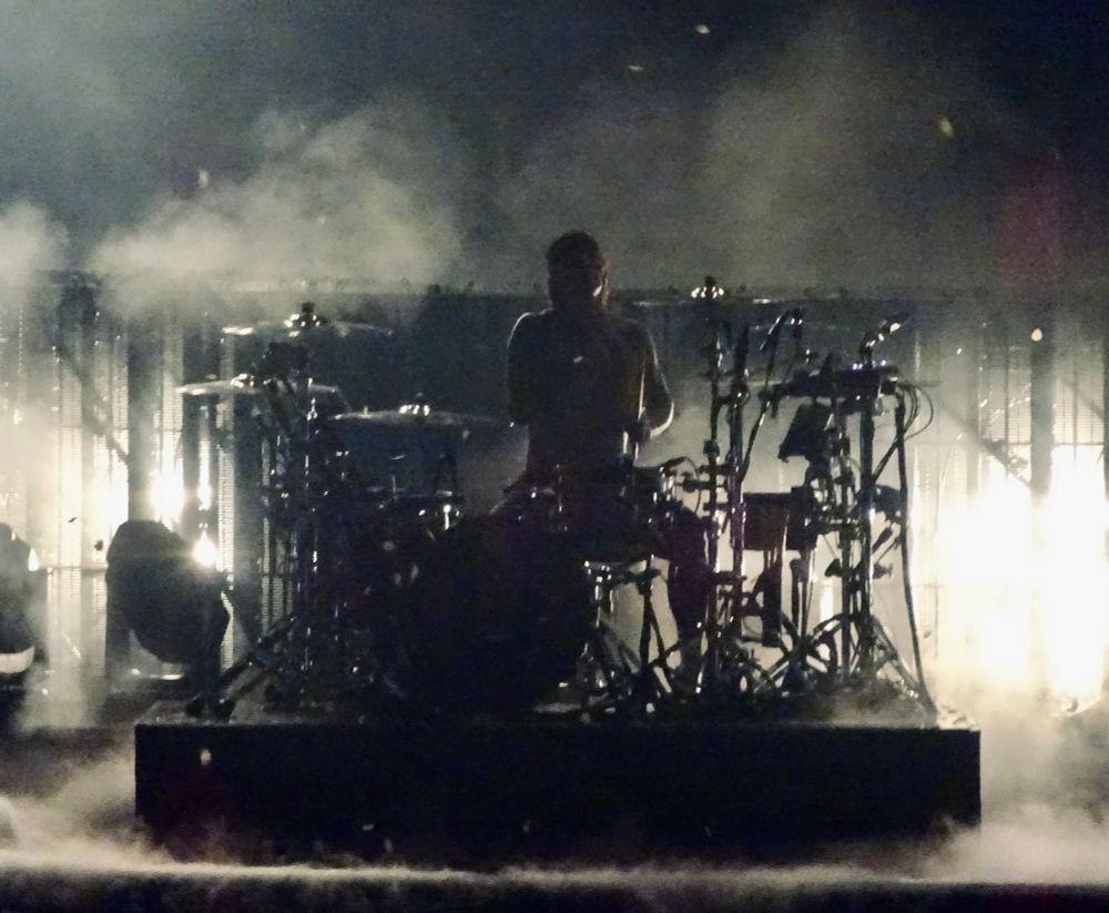 Twenty One Pilots performing at the O2 London - high contrast image of Josh playing the drums;