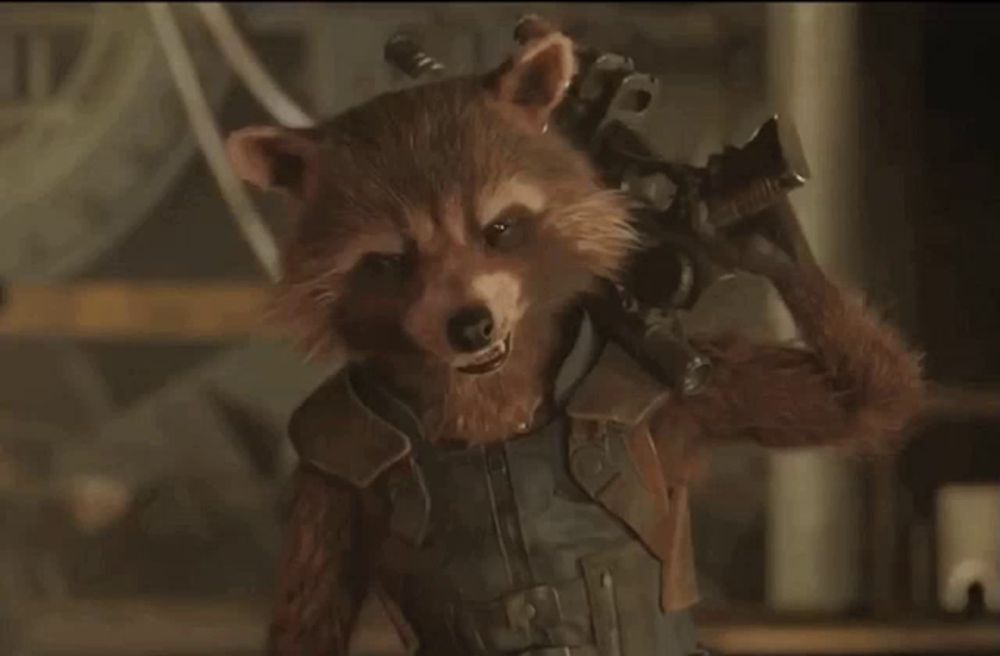 rocket raccoon from guardians of the galaxy is holding a gun in his hand and smiling .