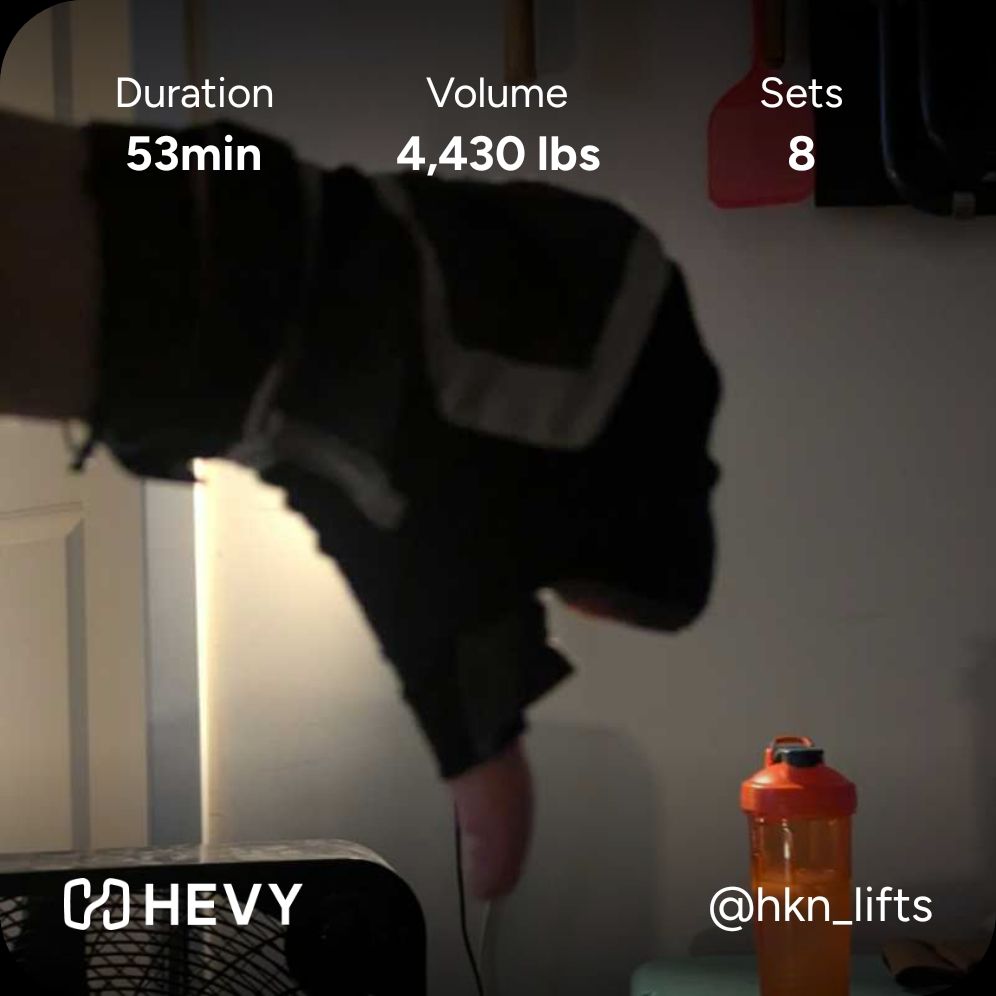 backlit blurry fingerless gloved thumbs down in front of the garage wall with a red shaker bottle off to the right, hevy app overlay reads 53 mins, 4,430 lbs volume, 8 sets