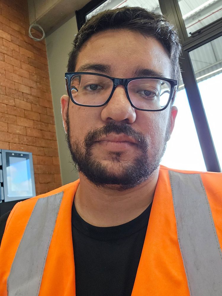 Homem, barba preta, cabelo curto preto, óculos, colete refletivo