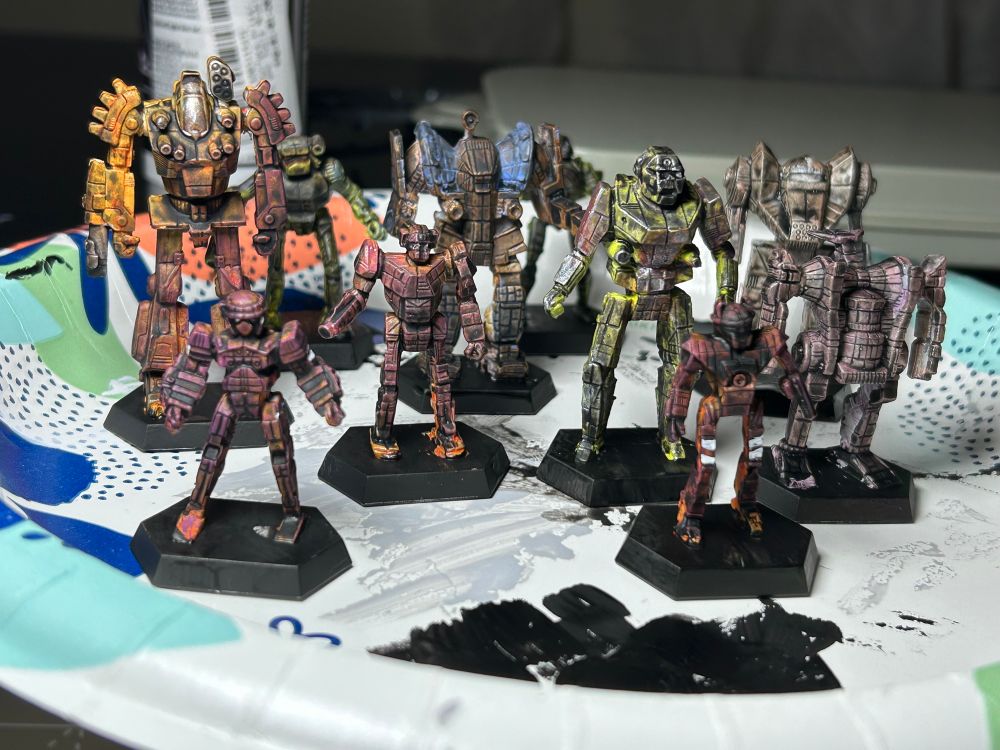 An assortment of battle tech miniatures painted rusted psychedelic colors