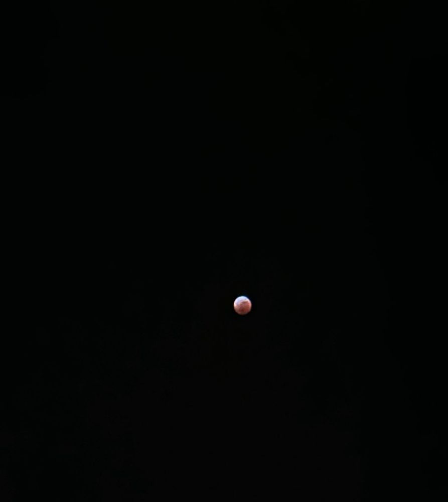 Reddish blood moon eclipse (about 3/4 covered) on a black sky