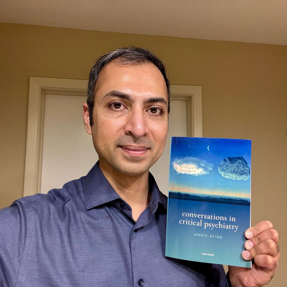 Me holding the book, “Conversations in Critical Psychiatry”