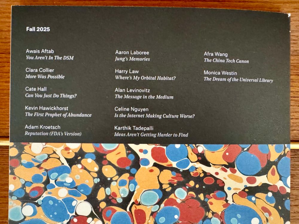 The back cover of the asterisk magazine for Fall 2025 is shown, listing contributors and their article titles in white text on a black background. Names include Awais Aftab, Cate Hall, Alan Levinovitz, Afra Wang, and others. The lower portion displays the same marbled pattern of blue, orange, red, and white circles and swirls seen on the front cover.