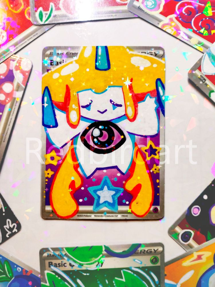 An energy card from the pokemon tcg, a jirachi is painted on it with posca pens
