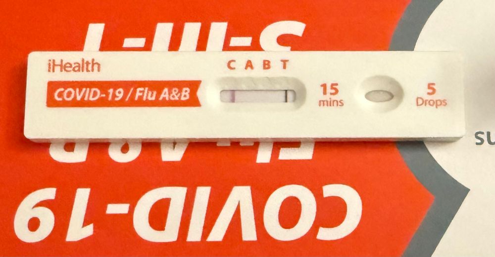 Photo of a 3-in-1 COVID & Flu rapid test, showing that I’ve tested positive for COVID
