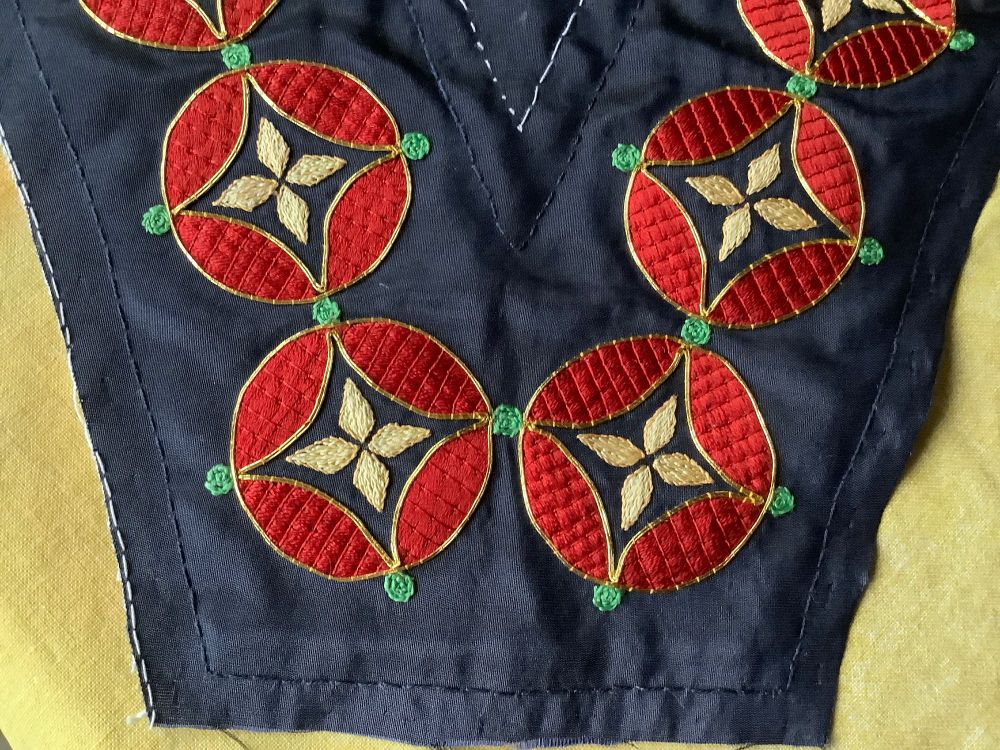 Dark blue taffeta silk ground with medieval quatrefoil design embroidery. Red silk couching, outlined with gold surface couching, and green split stitch dots