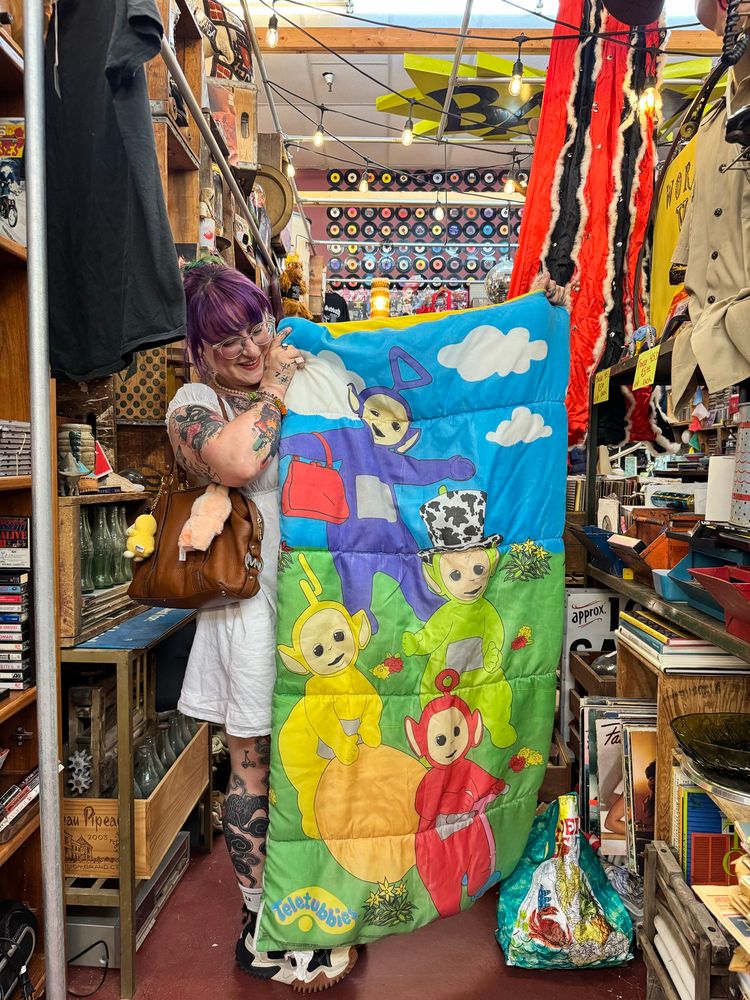 A person holding a vintage teletubbies sleeping bag