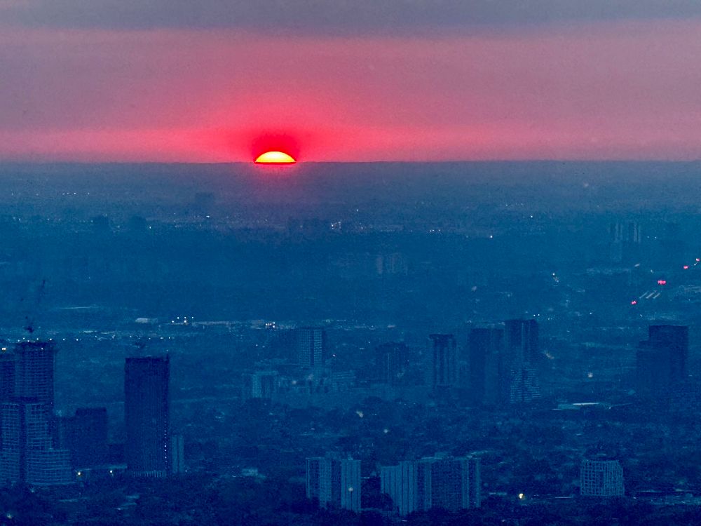 Sun about to dip below the horizon in a view across Toronto from the CN Tower 