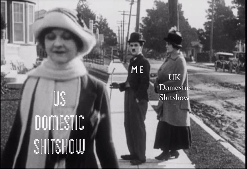 Charlie Chaplin with a “Me” label is looking at a Woman with the label “US Domestic Shit show” whilst another Woman to his side is looking at him with the label “UK Domestic Shit Show” ala the distracted boyfriend meme
