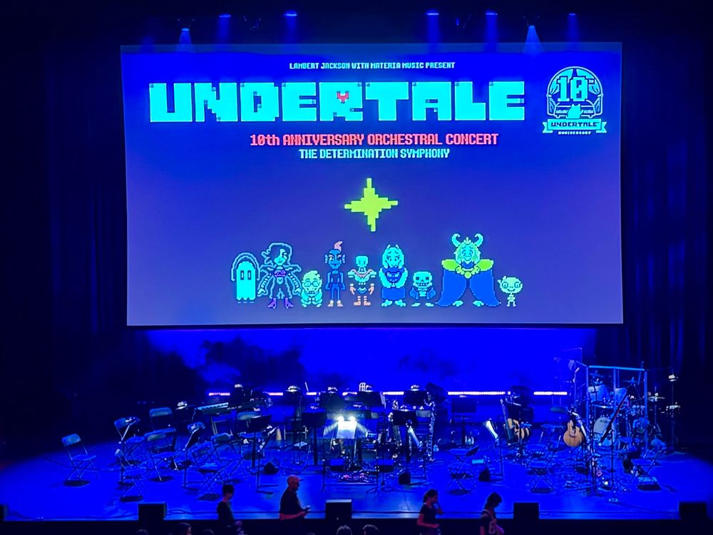 Picture of the stage at the At the 10th Anniversary Undertale concert. Shows a projected backdrop with characters from the game & the stage ready to receive the  Orchestra