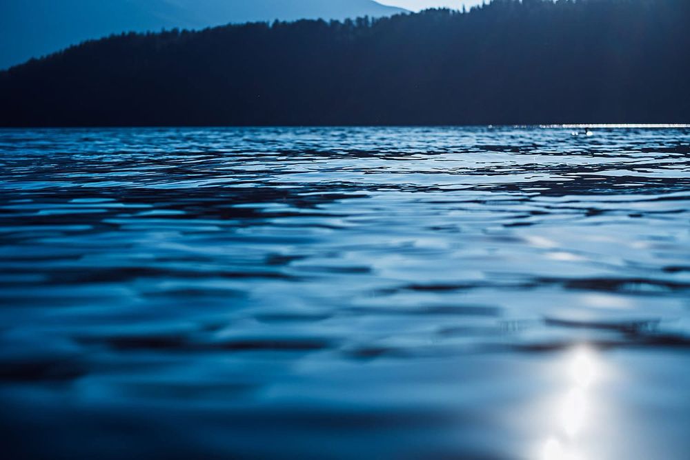 Water, ripples, light reflecting on surface,mountain in background. 