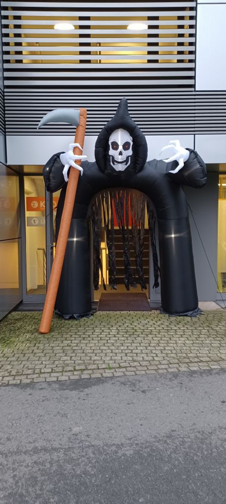 Eine riesige aufgeblasene Halloween Dekoration, die den kompletten Eingang der KFO Praxis umsäumt in Form eines Skelettes mit schwarzem Umhang und Sense